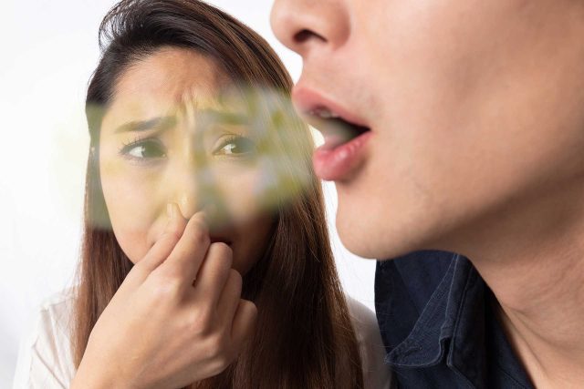 lady holding nose due to bad breath or halitosis